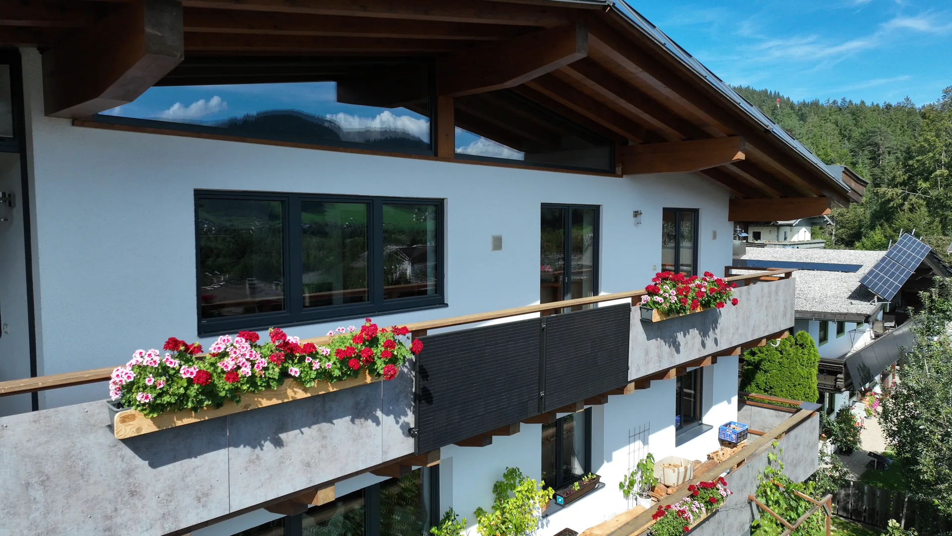 Balkone des FALKENSITZ Apartment mit roten und rosa Geranien in Ellmau