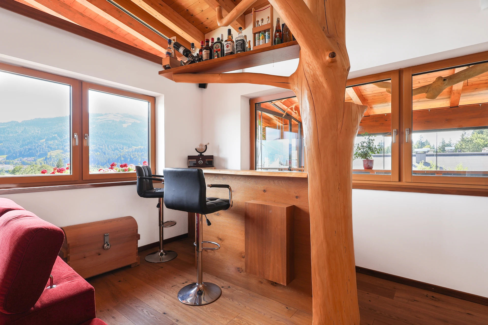 Die außergewöhnliche natürliche Baumkonstruktion im Wohnzimmer mit Bar und Bergblick — das Herzstück des FALKENSITZ