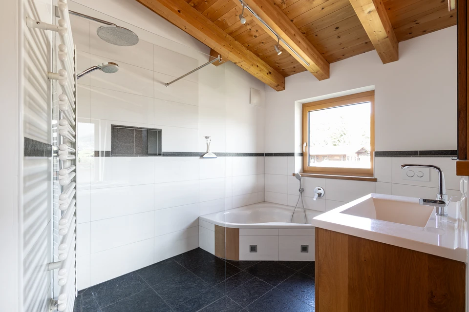 Das offene Master-Bad mit Regendusche, Badewanne und Holzbalken im FALKENSITZ