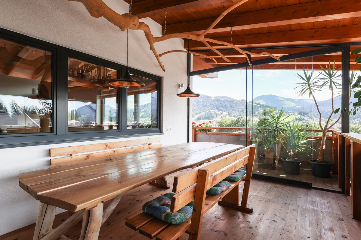 Panorama-Terrasse mit Holzboden, Geranien und Bergblick im FALKENSITZ Ellmau