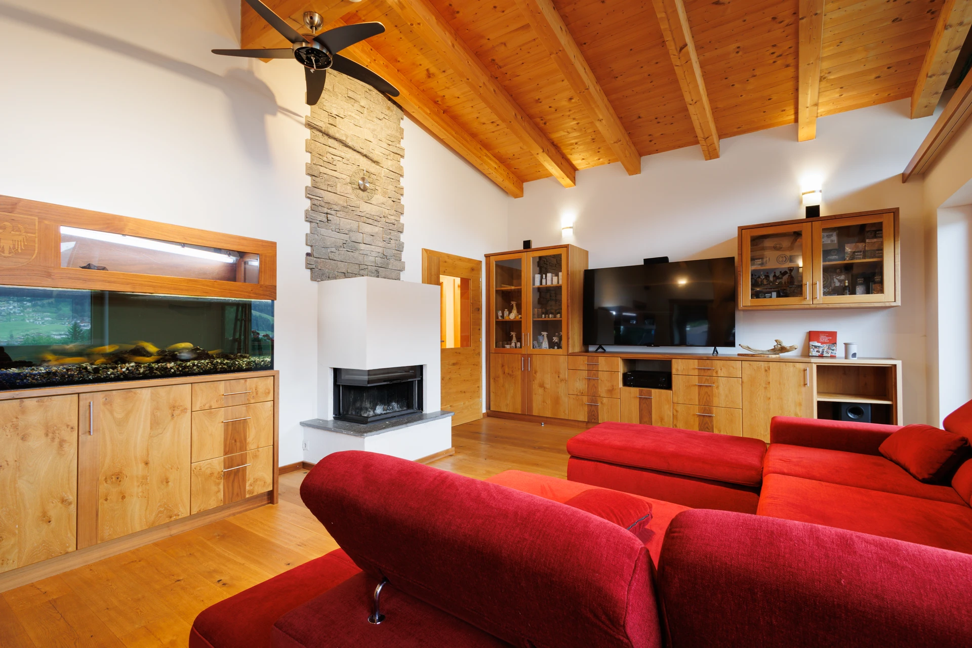 Wohnzimmer im FALKENSITZ mit Sichtdachstuhl, Kamin, TV-Wand und integriertem Aquarium