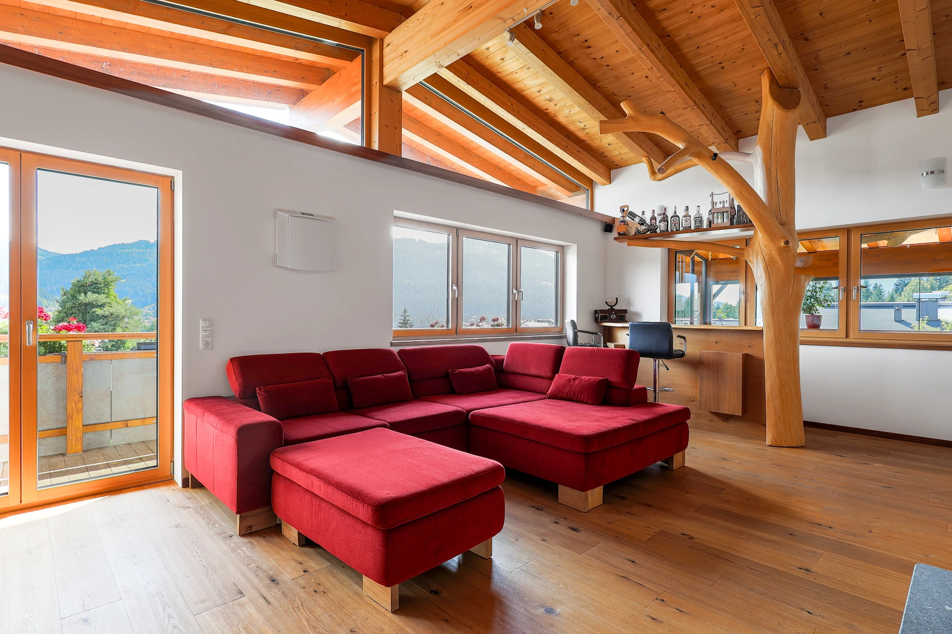 Couch-Lounge mit Ottomane, Baum-Konstruktion und Bar im FALKENSITZ Wohnzimmer — mit freiem Blick auf Tal und Berge